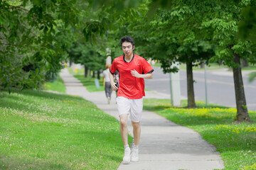 A young man is jogging  with music in the city.
