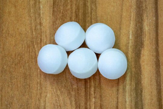 White Naphthalene mothballs isolated on wooden background. It is also known as moth flakes, naphthalin, naphthaline, antimite, albocarbon, hexalene, tar camphor, and white tar.