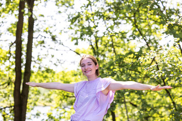 A cheerful young woman dances gracefully in natures beauty, surrounded by lush greenery and...
