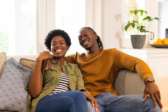 Smiling African American couple relaxing on couch at home, enjoying quality time together