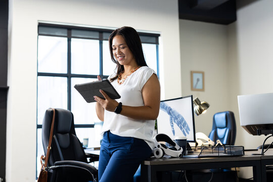 Using digital tablet, woman smiling and working in modern office with robotics