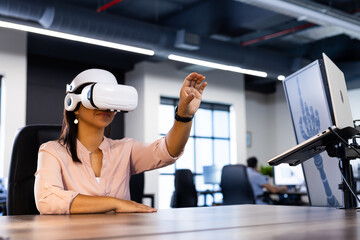 Using VR headset, woman interacting with virtual environment in modern office