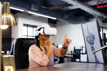 Using VR headset, woman interacting with virtual robotic hand in modern office