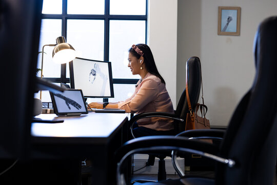Working in office, woman using computer with robotic arm on screen