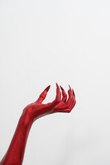 A witch's hand with long red nails on a white background, resembling a demon's or zombie's hand. This scary monster is perfect for Halloween, symbolizing a resurrected fictional creature.