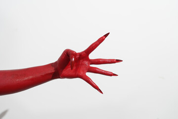 A witch's hand with long red nails on a white background, resembling a demon's or zombie's hand. This scary monster is perfect for Halloween, symbolizing a resurrected fictional creature.