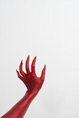 A witch's hand with long red nails on a white background, resembling a demon's or zombie's hand. This scary monster is perfect for Halloween, symbolizing a resurrected fictional creature.