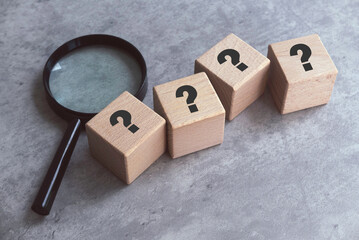 Wooden Cube with Question Mark Symbol and magnifying glass.