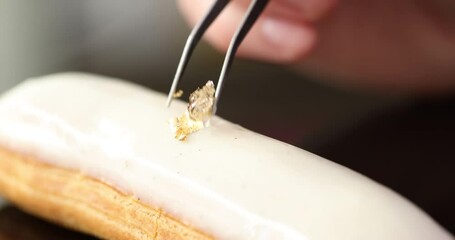 Adding gold flakes to eclair with white frosting - Powered by Adobe