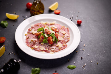 cooking tuna carpaccio - cherry tomato pieces on a plate with raw tuna fillet slices