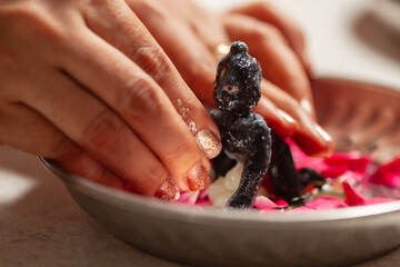 An Indian woman applying ghee to the Hindu god 'Krishna' (Laddu Gopal) after performing the 'snan ritual' during the Indian festival of Krishna Janmashtami.