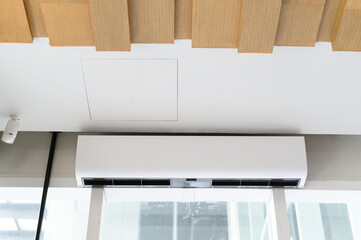 Air conditioning unit mounted on ceiling, providing cool air in modern interior space.