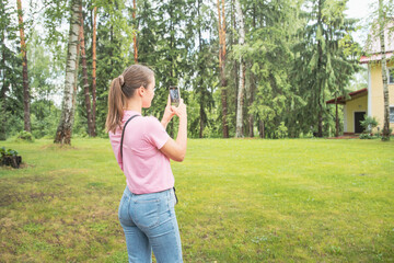 A woman is taking a picture of a tree with her cell phone