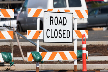 Road closed orange stripped sign near an ongoing construction