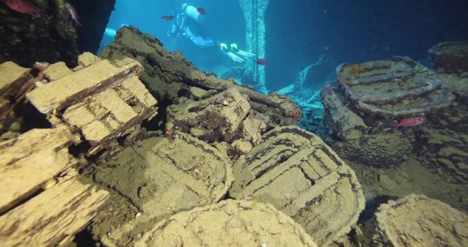 Divers explore the wreck of the SS Thistlegorm. Top diving wreck dives. Swimming over motorbikes and other cargo in hold of Thistlegorm shipwreck in the Red Sea, Sharm el Sheikh, Egypt.