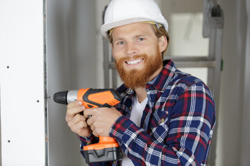 construction worker with cordless drill drilling wall