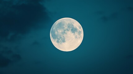 A serene night sky featuring a bright, luminous full moon against a backdrop of soft clouds and deep blue hues.