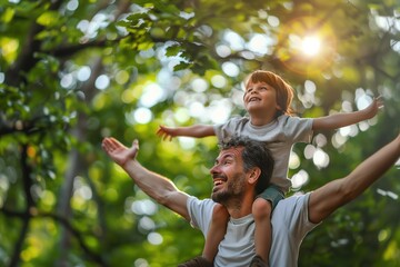 Portrait of happy father giving son piggyback ride on his shoulders and looking up. Cute boy with dad playing outdoor