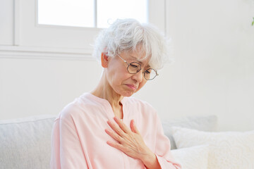 胸焼けがするシニア女性　リビングルーム