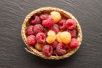 Fresh sweet raspberries in a straw plate, macro, top view.