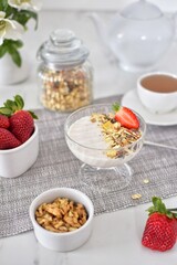 Muesli with yogurt and strawberries, tea.  Healthy breakfast.