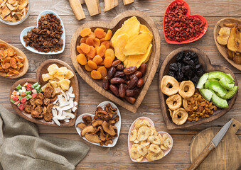 Healthy sweet dried fruits and berries in wooden heart shaped plates on wooden background.Top view.