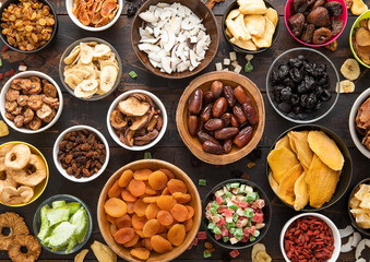 Mixed healthy dried sweet berries and fruits snack in various bowl plates on wooden background.Top view.