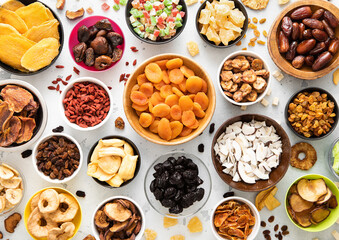 Assorted organic dried sweet fruits and berries in various bowl plates on light kitchen background.Top view.