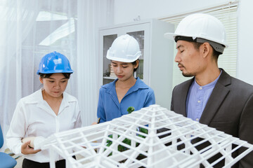 An office filled with a diverse team of professionals brainstorming and discussing computers and blueprints. An environment that showcases modern architecture and collaborative teamwork.