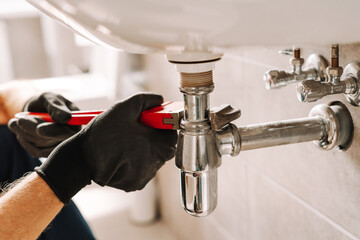 Plumber using adjustable wrench for repairing sink pipe