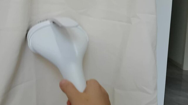 Femal hand steams a white cloth with a hand iron and smooths out the creases on it. Housewife chores, tidying up, cleanliness, domestic lifestyle. High quality 4k footage