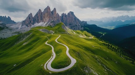 Aerial shot of the stunning Italian Dolomites, with jagged peaks, alpine meadows, and winding mountain roads