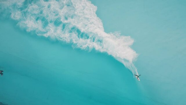Surfing in the pool. Top down aerial view of the surfers riding wave in the pool