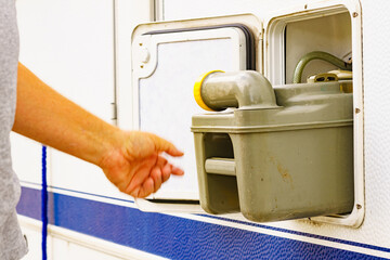 Man serving caravan, tank toilet cassette in dump station.