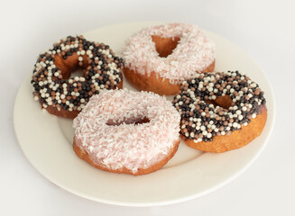 donuts with different toppings on a light background, not a healthy diet, fatty and unhealthy food, sweet pastries, donut day, Fat Thursday
