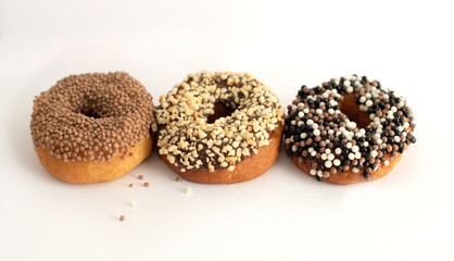 donuts with different toppings on a light background, not a healthy diet, fatty and unhealthy food, sweet pastries, donut day, Fat Thursday
