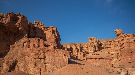 a striking range of massive red sandstone formations under a vast blue sky, hinting at a tranquil desert setting in the warm, gentle light of a late summer afternoon