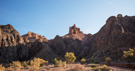 a striking desert scene with rugged mountains and a distinctive rock formation that resembles a...