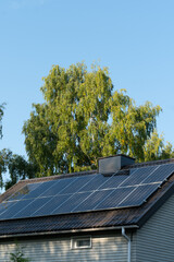 solar panels on home roof against blue sky and trees. green energy concept.