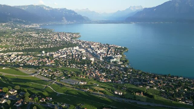 Reveal drone shot above Vevey in the Lavaux with the Lake of Geneva and the Swiss Alps behind.