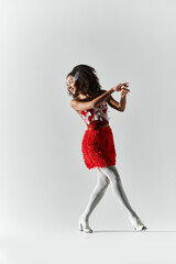 A young woman with curly hair showcases her stylish red ensemble while confidently striking a pose.