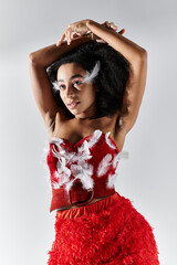A young woman shows elegance and confidence in a vibrant red ensemble adorned with feathers.