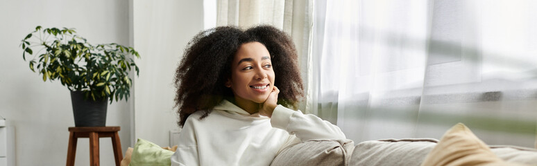 A joyful young woman relaxes at home, embracing the comfort of her cozy outfit in the living room.