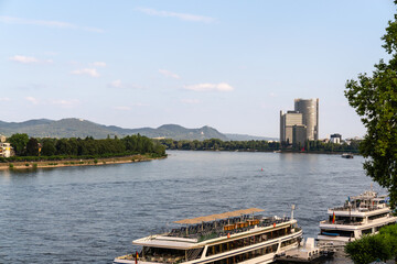 Ausblick auf den Rhein in Bonn mit Blick, Richtung Siebengebirge und Drachenfels. Im Sommer bei blauem Himmel und Sonnenschein ein Boot im Vordergrund, direkt am Fluss