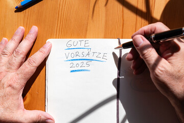 Die Hände eines Mannes Menschen schreiben in ein Notizbuch, seine guten Vorsätze für das neue...