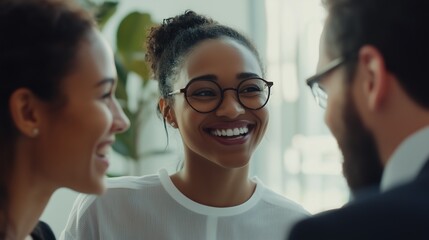 Two women and a man are seen laughing and exchanging ideas during an informal meeting in a bright, open workspace. The setting emphasizes creativity, collaboration, and a supportive team culture.