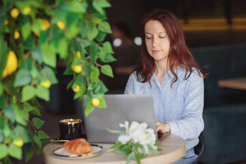 Female freelancer working from a cafe with a laptop and coffee