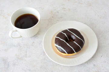 a striped donut on a plate with a cup of strong coffee 