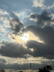 a dramatic sky with large, dark clouds that are illuminated by the sun, creating a striking contrast between light and shadow