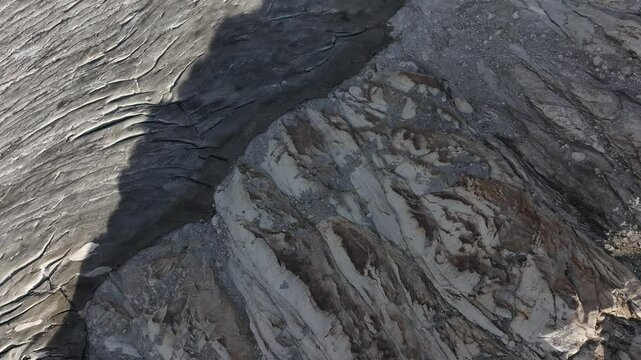 Birds eye view of sunlit white rocky mountain surface with nearby lake at Rhonegletscher, Furkapass, Switzerland.